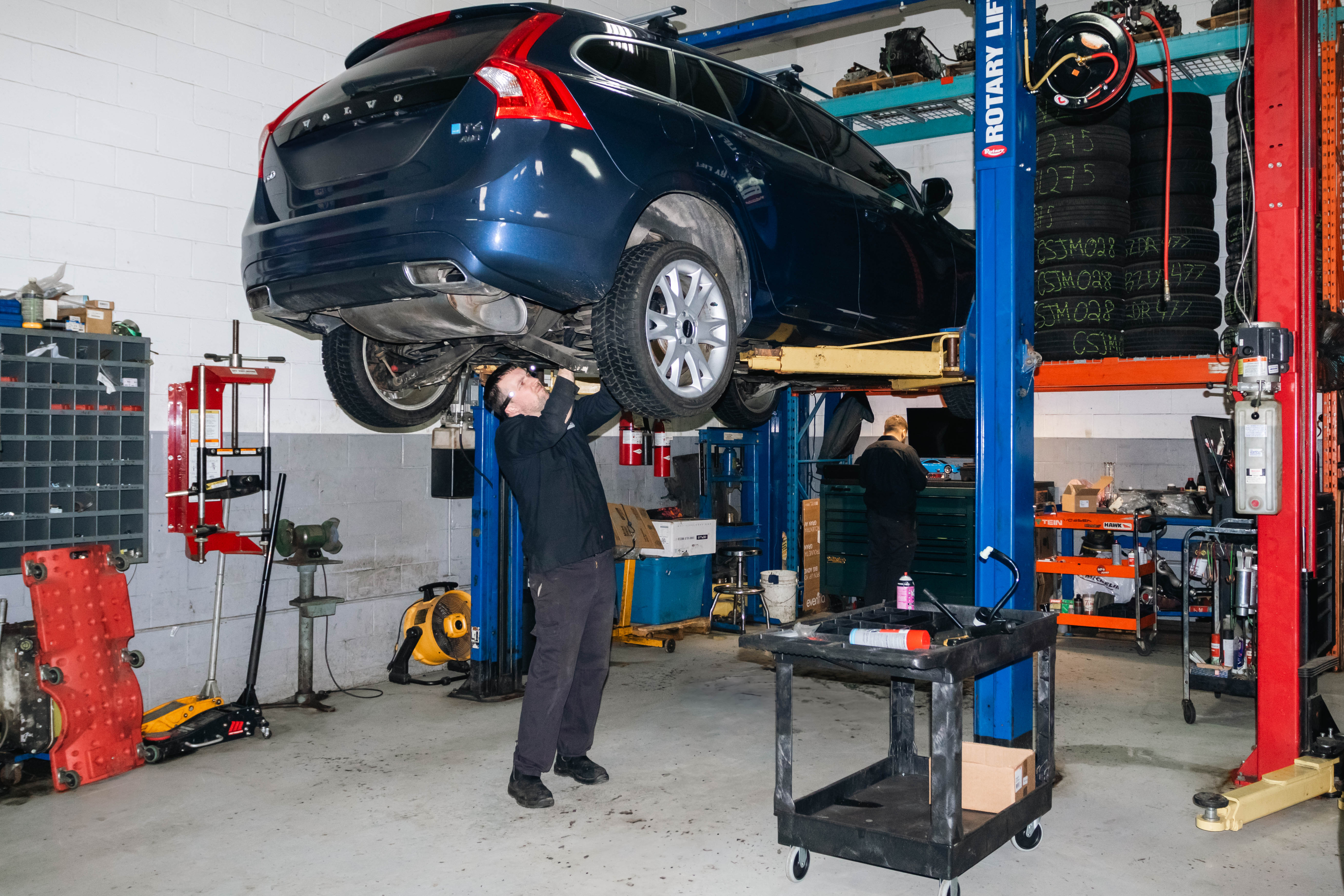 Mechanic working under a lifted vehicle in a workshop